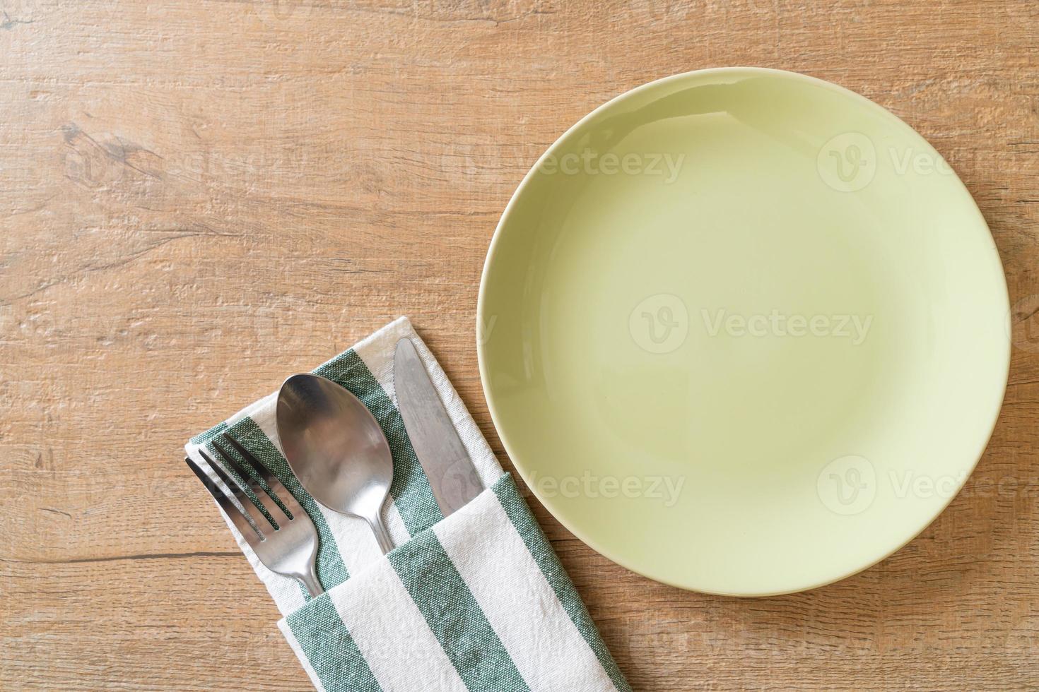 Empty plate or dish with knife, fork, and spoon on wood tile background photo