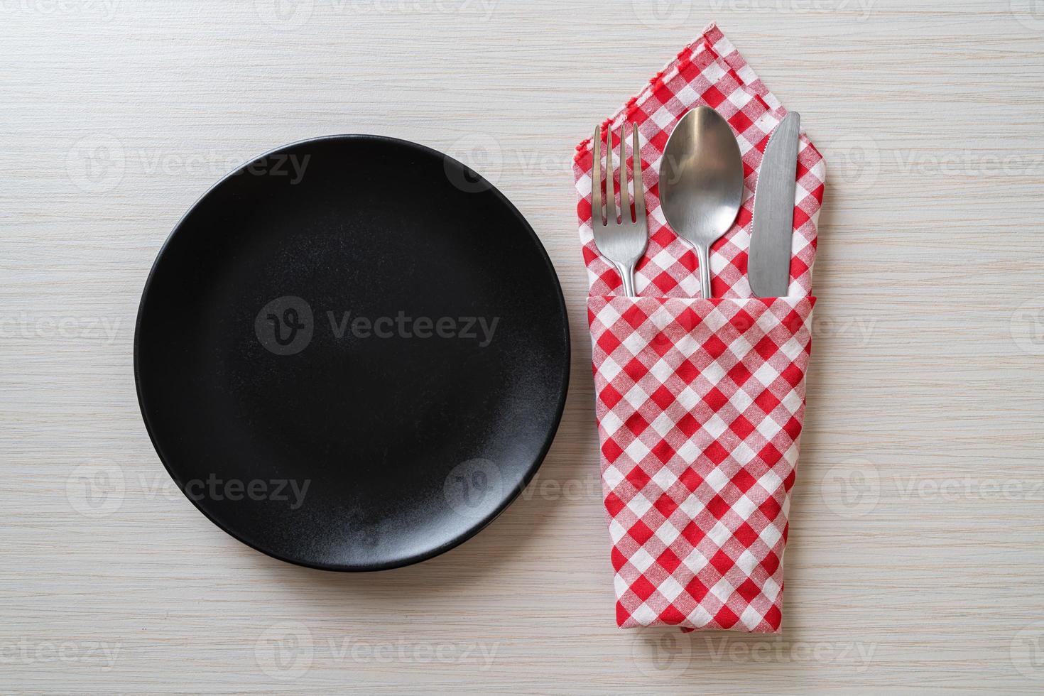 Empty plate or dish with knife, fork, and spoon on wood tile background photo