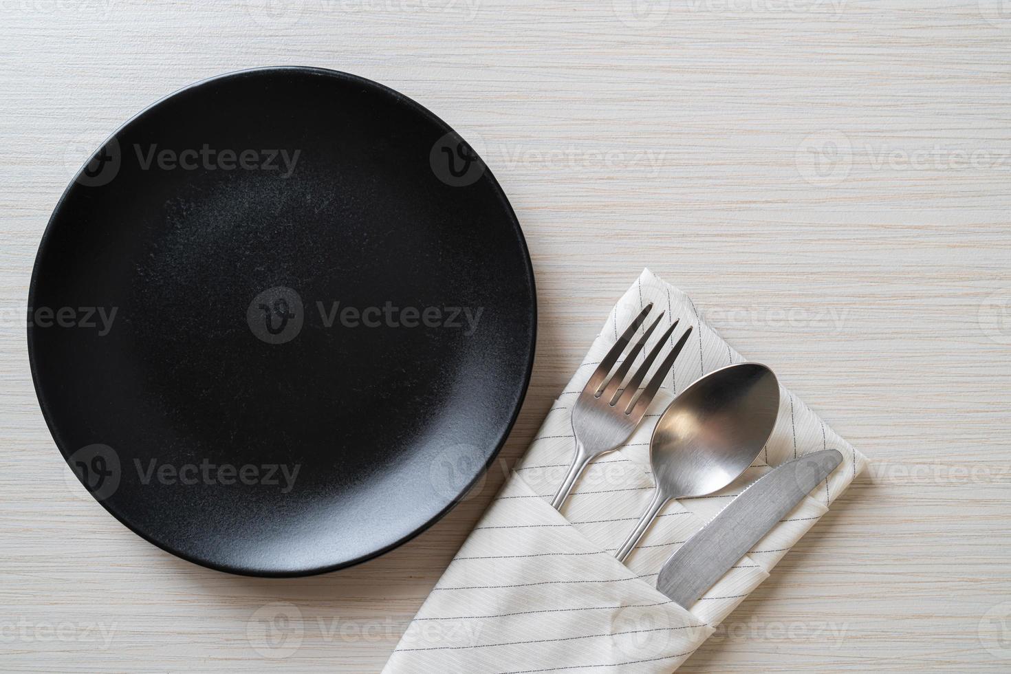 Empty plate or dish with knife, fork, and spoon on wood tile background photo