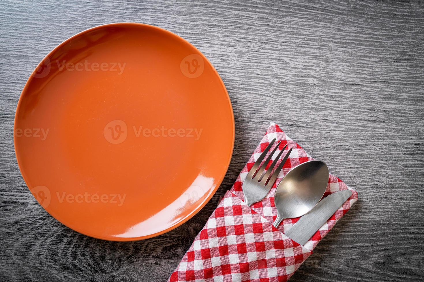 Empty plate or dish with knife, fork, and spoon on wood tile background photo