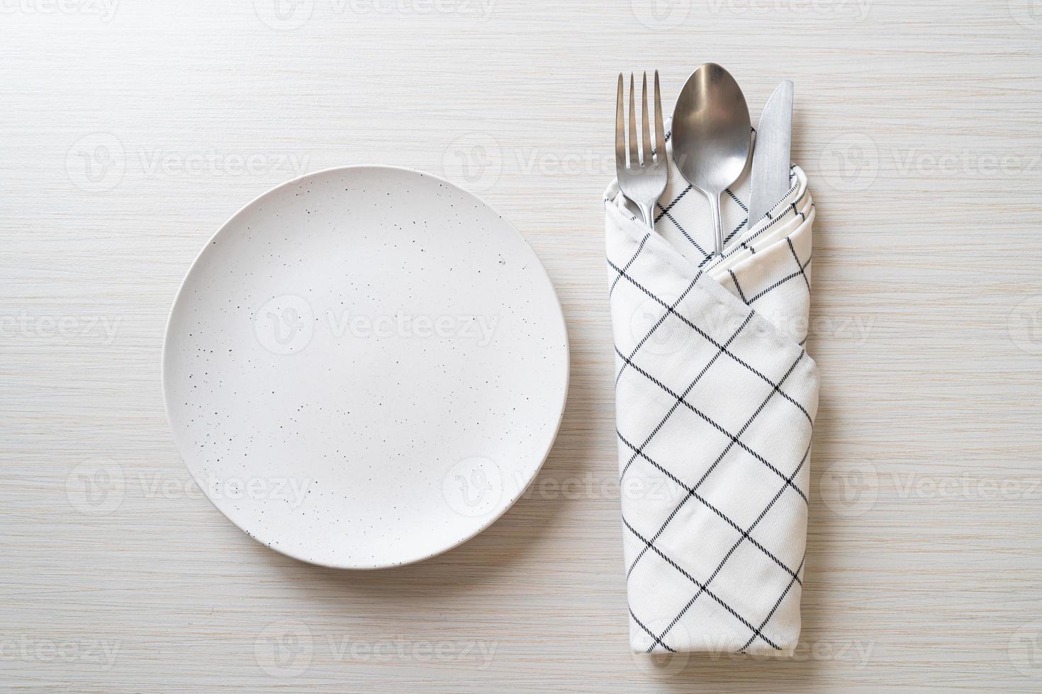 Empty plate or dish with knife, fork, and spoon on wood tile background photo