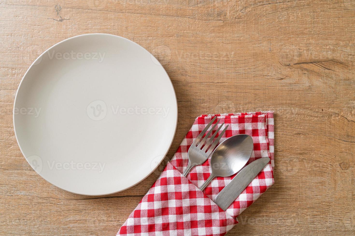 Empty plate or dish with knife, fork, and spoon on wood tile background photo