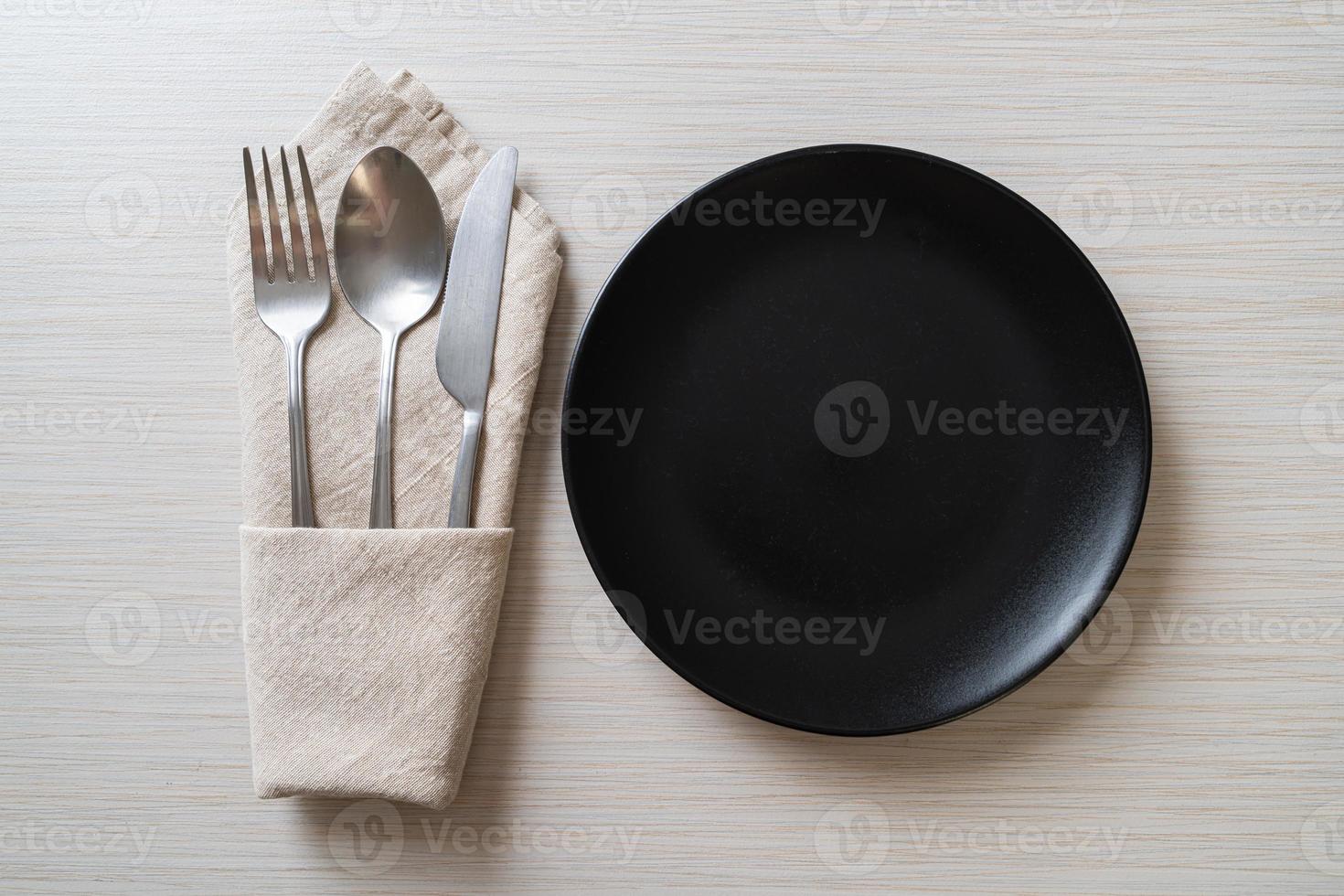 Empty plate or dish with knife, fork, and spoon on wood tile background photo