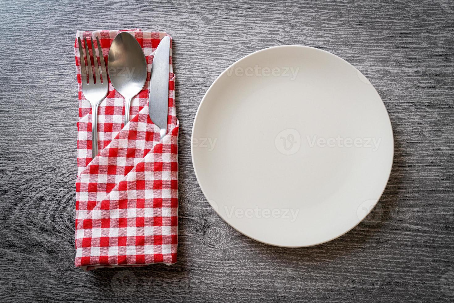 Empty plate or dish with knife, fork, and spoon on wood tile background photo