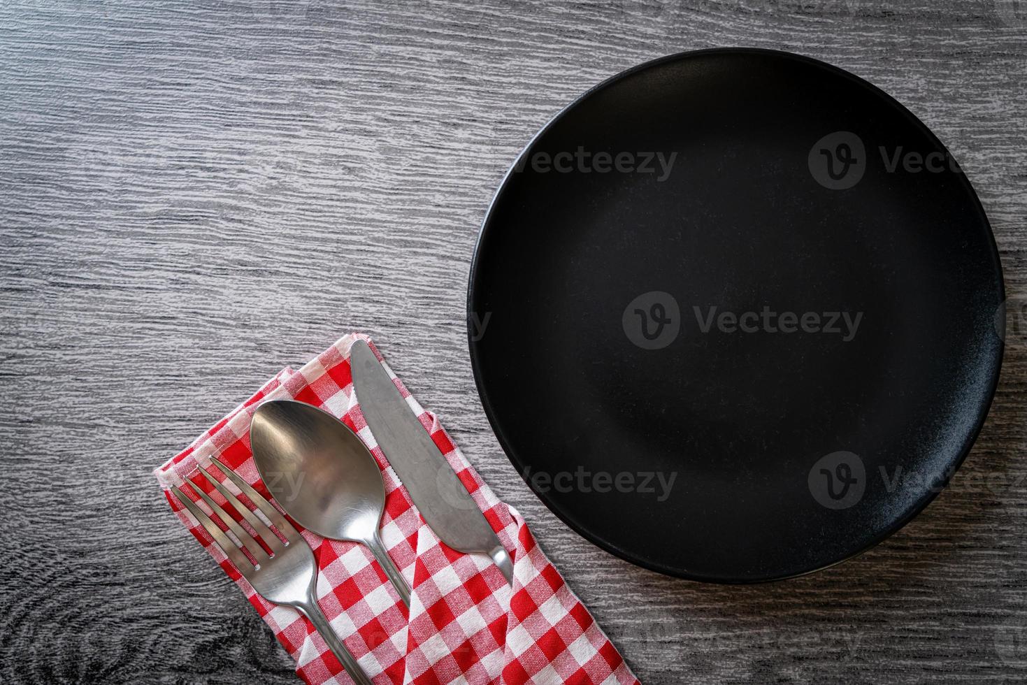 Empty plate or dish with knife, fork, and spoon on wood tile background photo