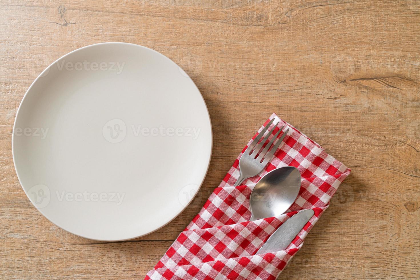 Empty plate or dish with knife, fork, and spoon on wood tile background photo