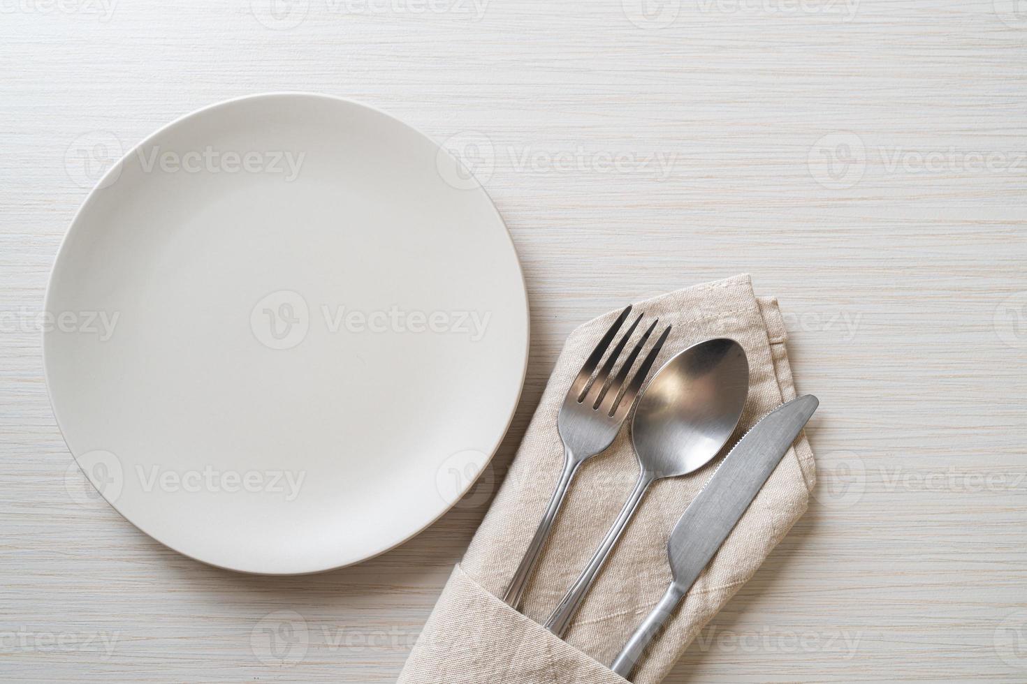 Empty plate or dish with knife, fork, and spoon on wood tile background photo