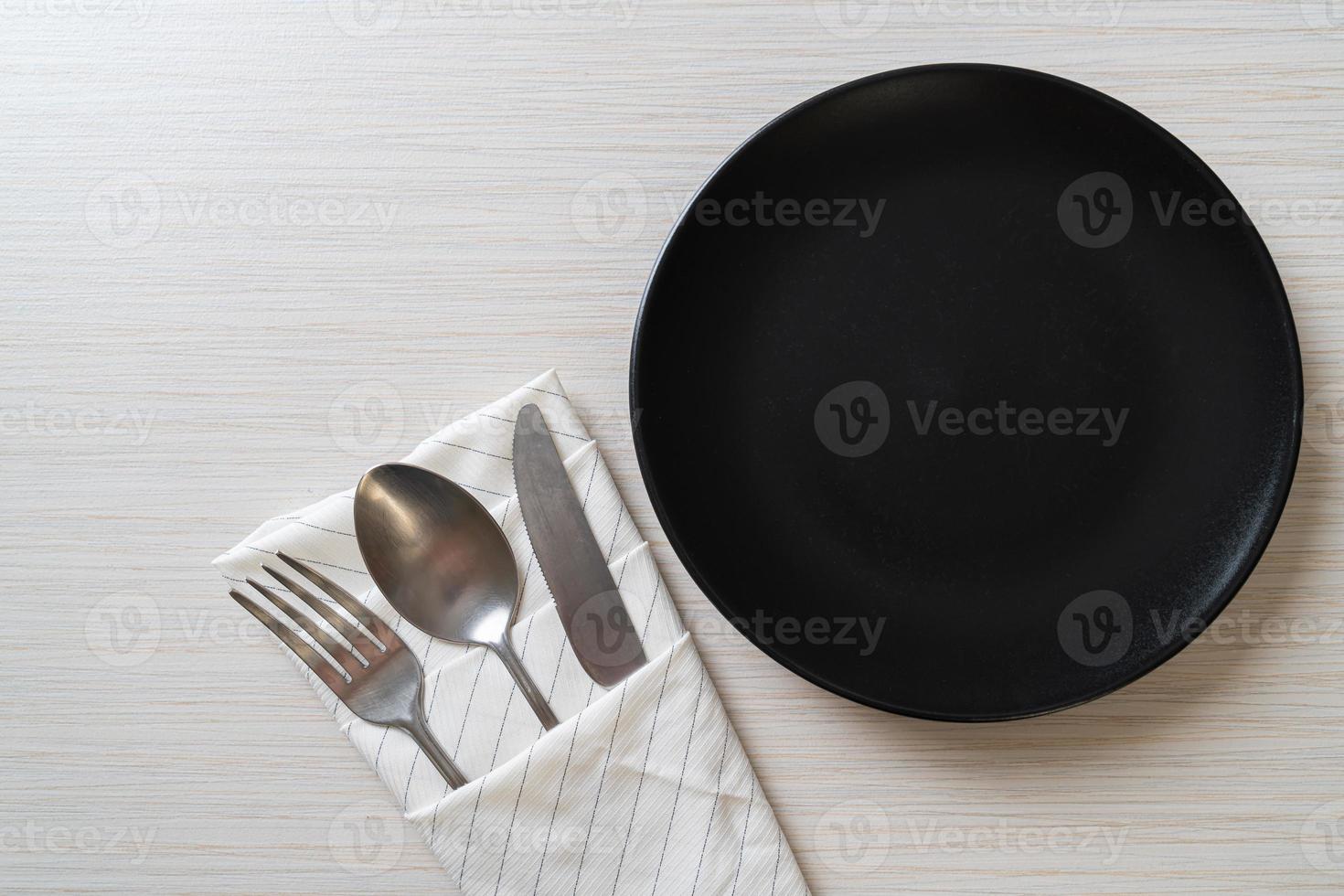 Empty plate or dish with knife, fork, and spoon on wood tile background photo