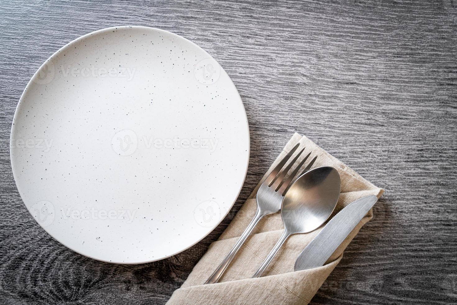 Empty plate or dish with knife, fork, and spoon on wood tile background photo