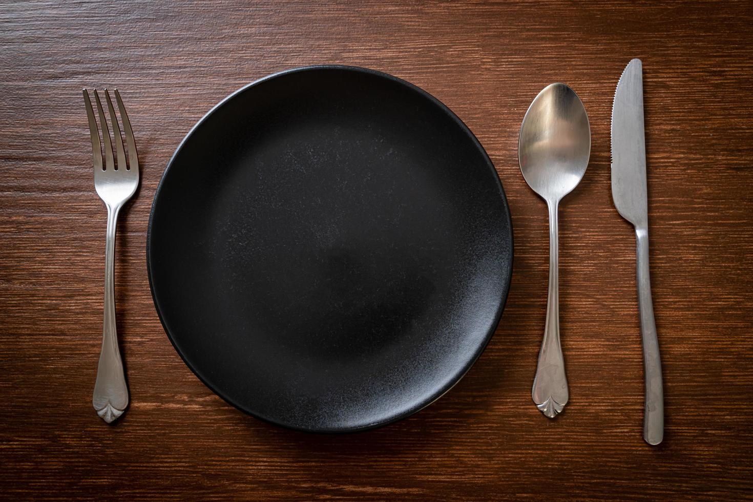 Empty plate or dish with knife, fork, and spoon on wood tile background photo