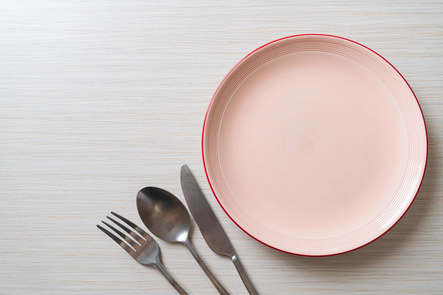 Empty plate or dish with knife, fork, and spoon on wood tile background photo