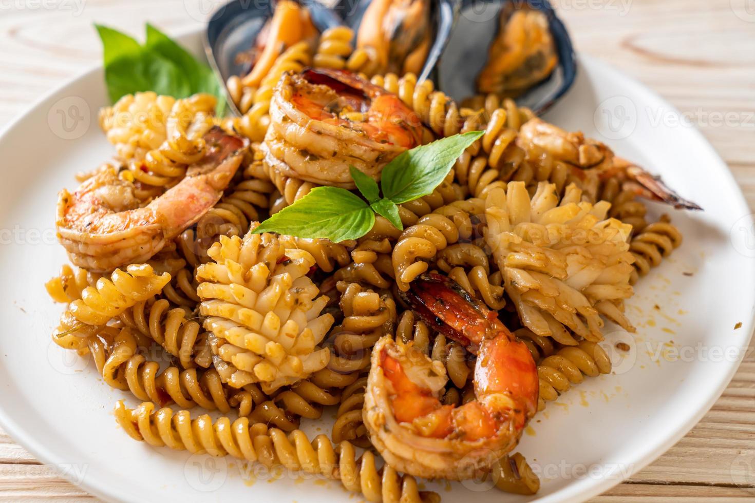 pasta en espiral salteada con salsa de mariscos y albahaca - estilo de comida fusión foto