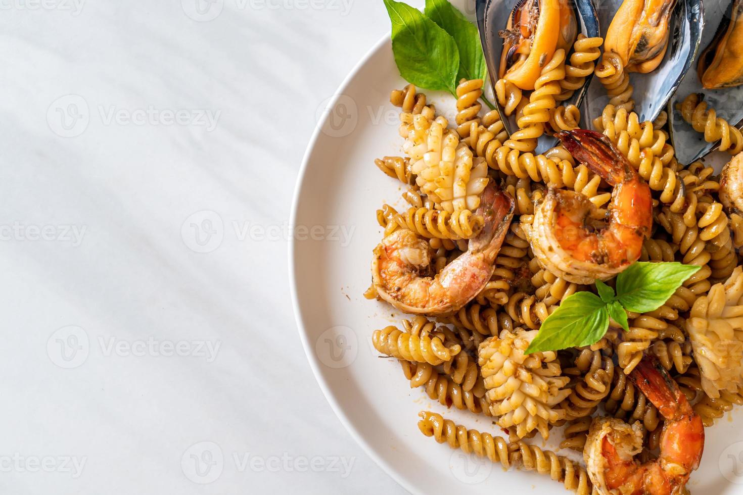 Stir-fried spiral pasta with seafood and basil sauce - fusion food style photo