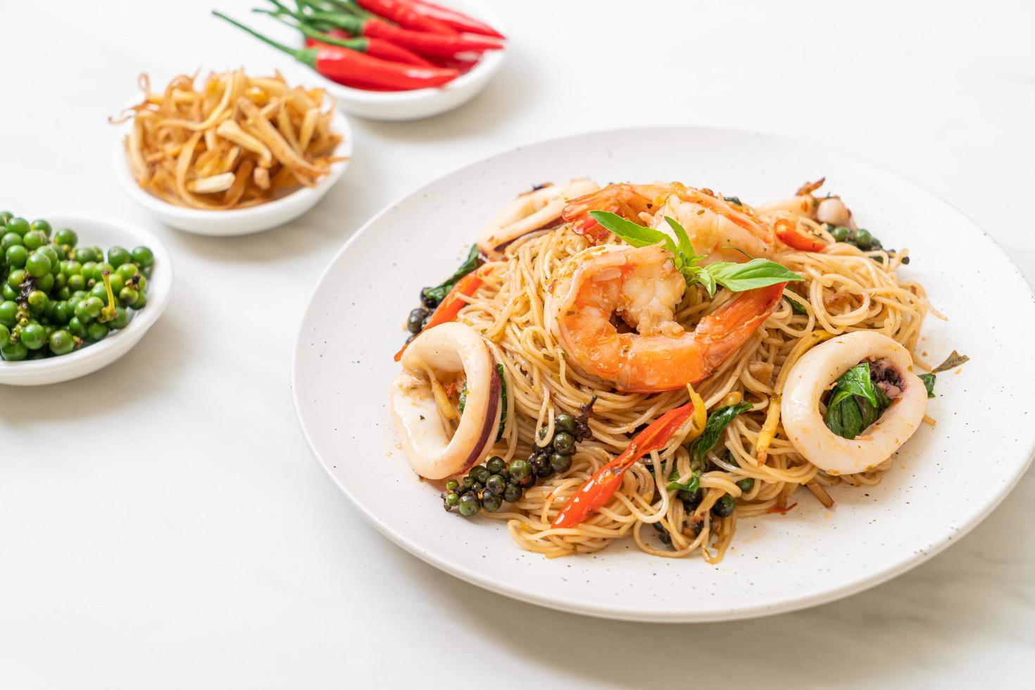 Stir-fried Chinese noodles with basil, chili, shrimp, and squid - Asian food style photo