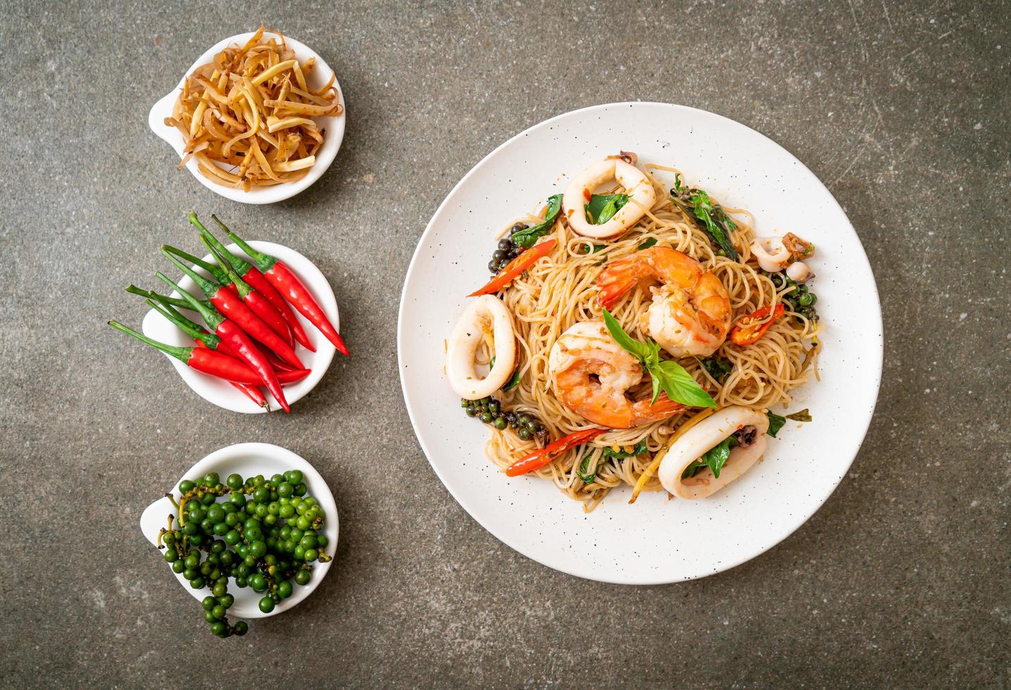 Stir-fried Chinese noodles with basil, chili, shrimp, and squid - Asian food style photo