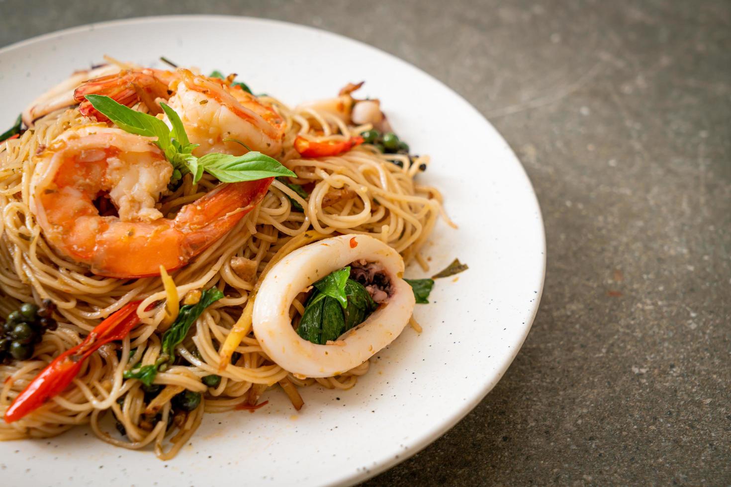 Stir-fried Chinese noodles with basil, chili, shrimp, and squid - Asian food style photo