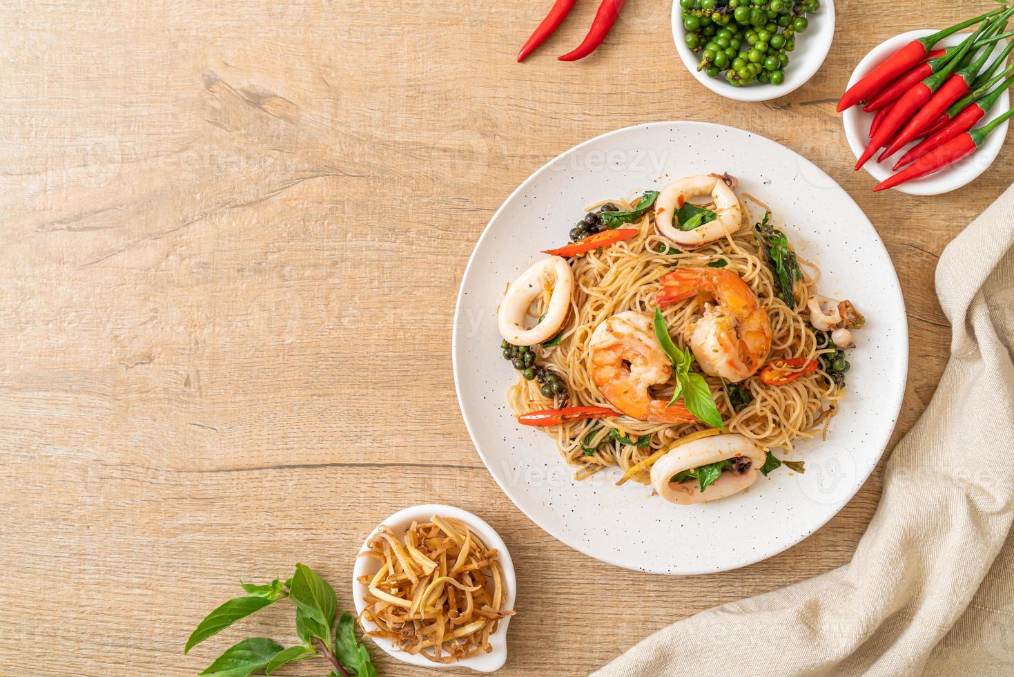 fideos chinos salteados con albahaca, chile, camarones y calamares - estilo de comida asiática foto