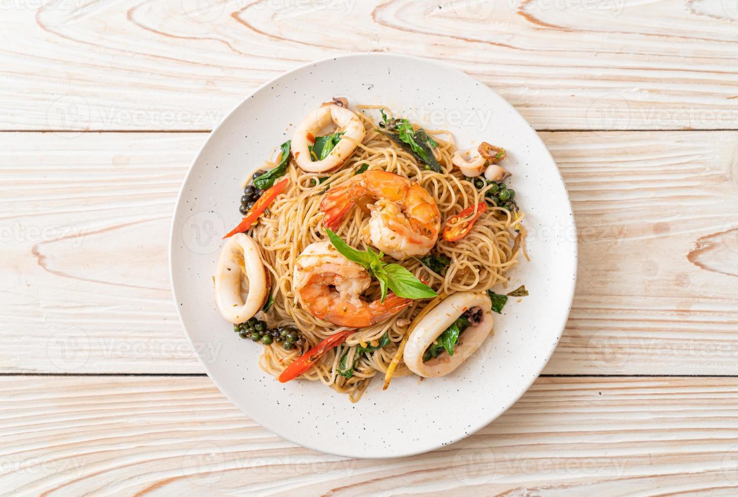 fideos chinos salteados con albahaca, chile, camarones y calamares - estilo de comida asiática foto