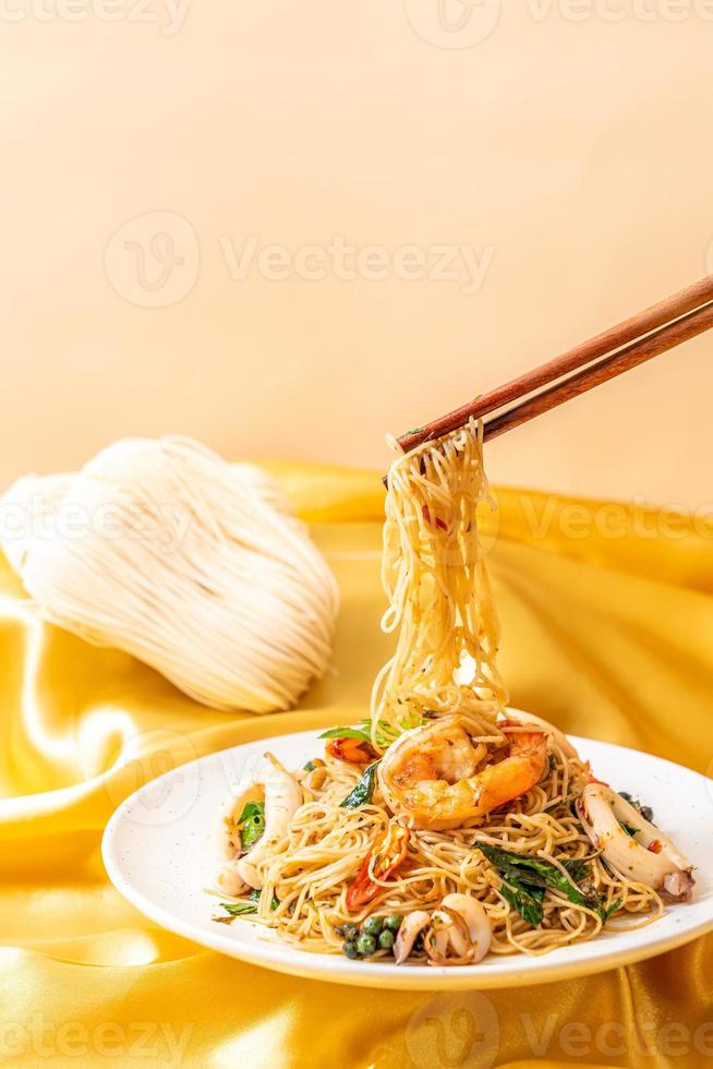 Stir-fried Chinese noodles with basil, chili, shrimp, and squid - Asian food style photo