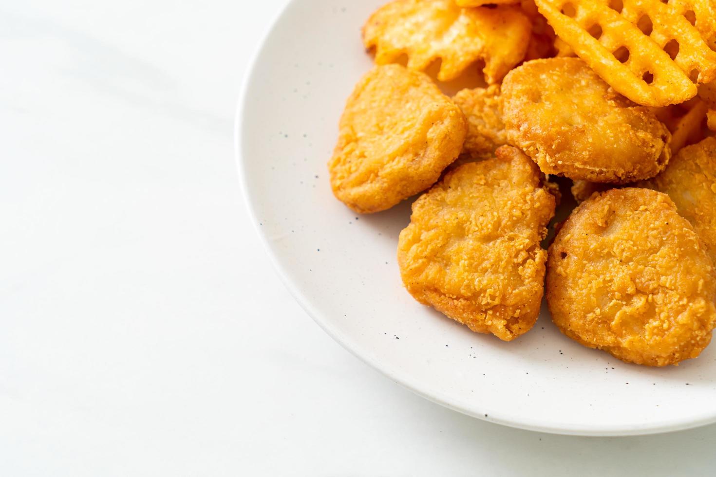 Fried chicken nuggets with fried potatoes on plate photo