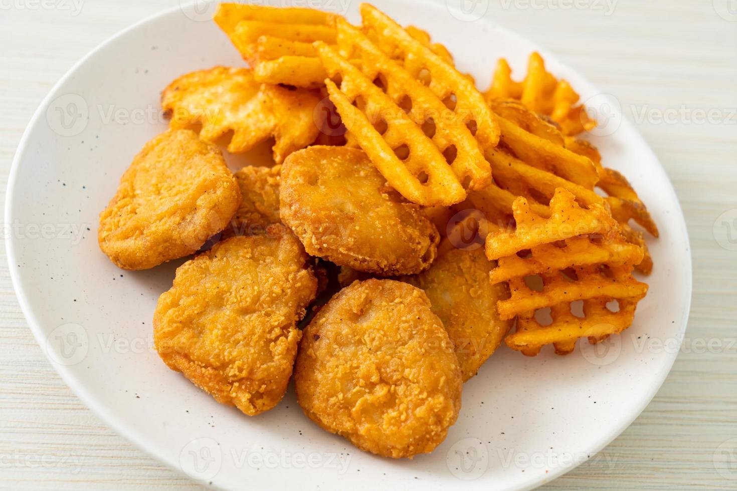 Fried chicken nuggets with fried potatoes on plate photo