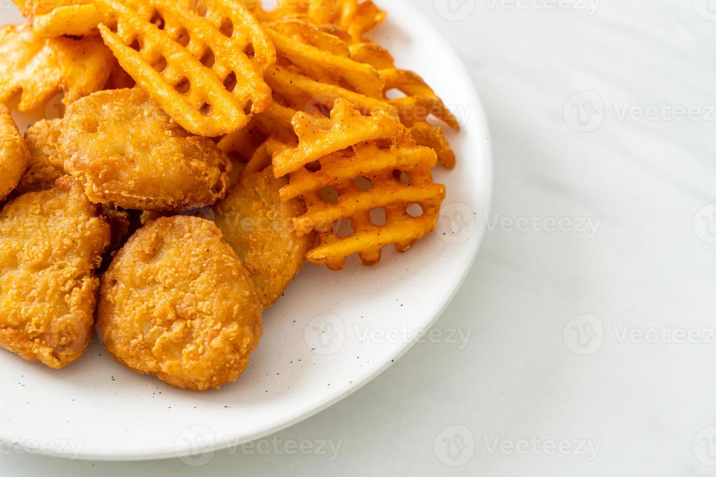 Fried chicken nuggets with fried potatoes on plate photo