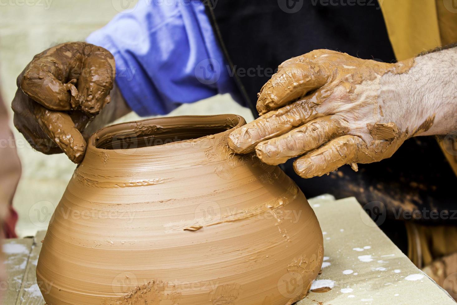 Manos de hombre trabajando y dando forma a arcilla, alfarero en alfarería foto