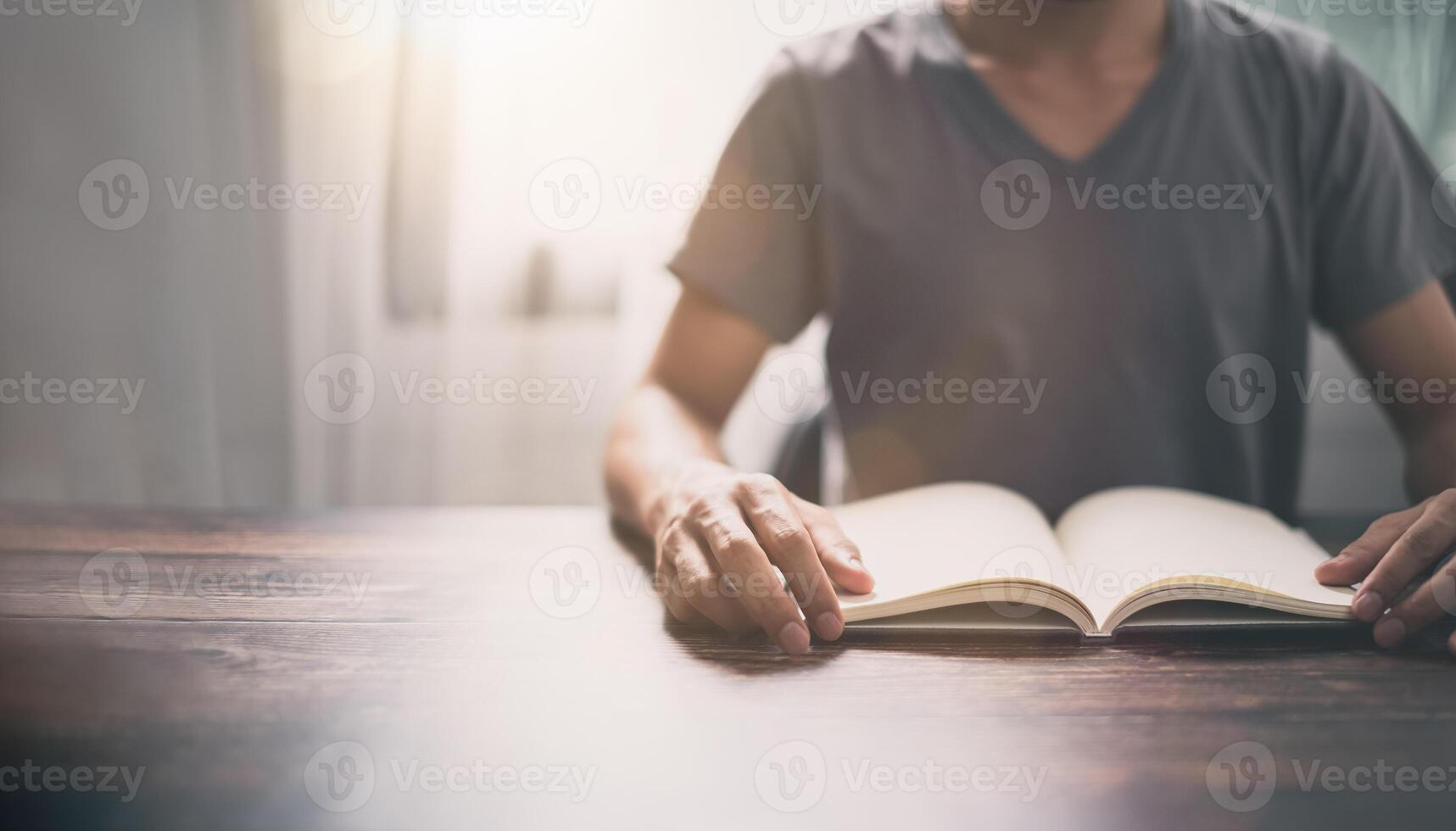 A man is reading a book on a table photo