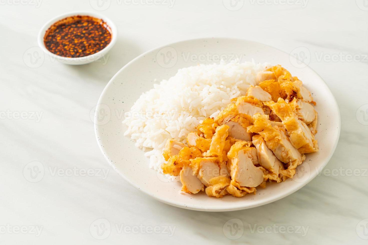 Fried chicken topped on rice with spicy dipping sauce photo