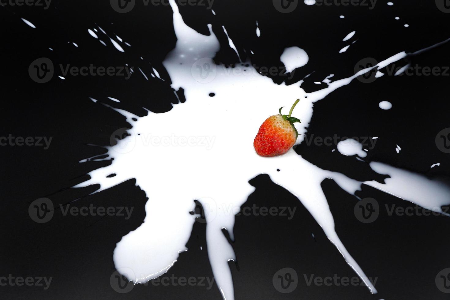 A fresh strawberry with splash milk on the black background photo