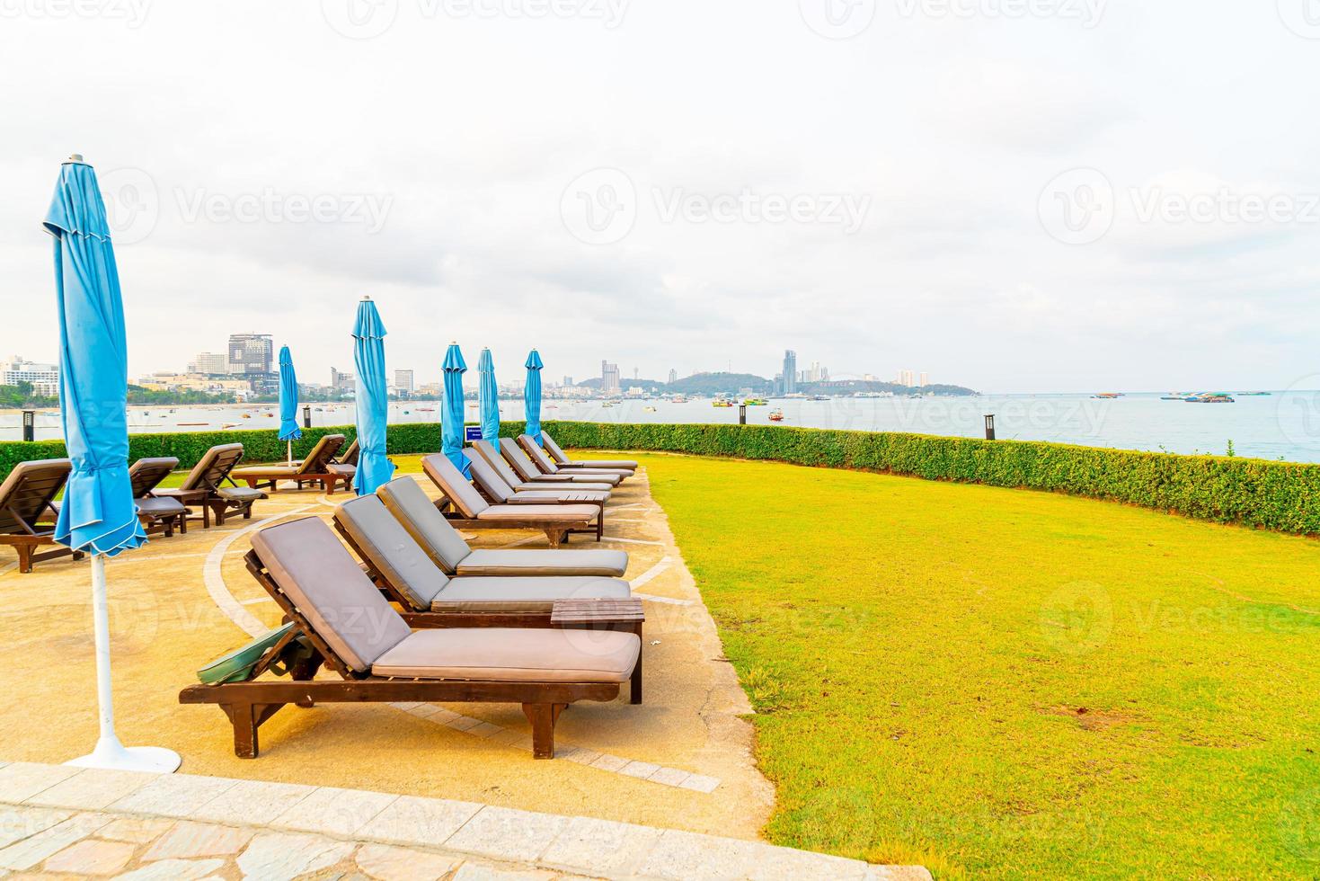 Chair pool or bed pool and umbrella around swimming pool with sea beach background at Pattaya in Thailand photo