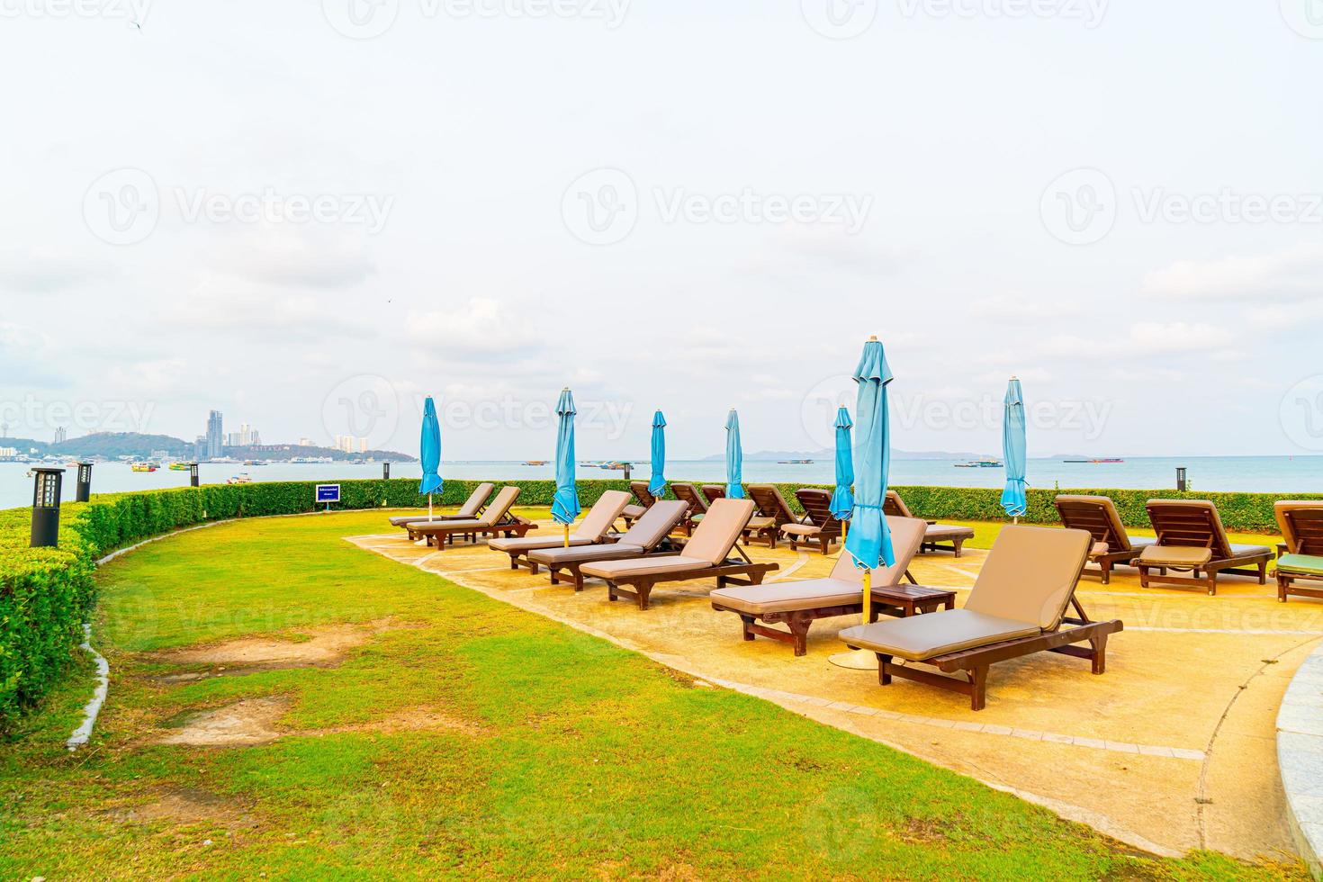 Chair pool or bed pool and umbrella around swimming pool with sea beach background at Pattaya in Thailand photo
