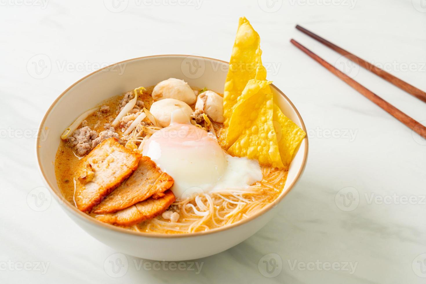 fideos de arroz con albóndigas, cerdo asado y huevo en sopa picante foto