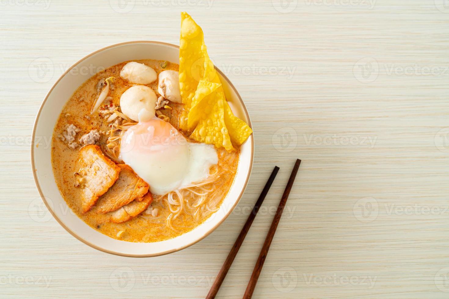 Rice vermicelli noodles with meatball, roasted pork and egg in spicy soup photo