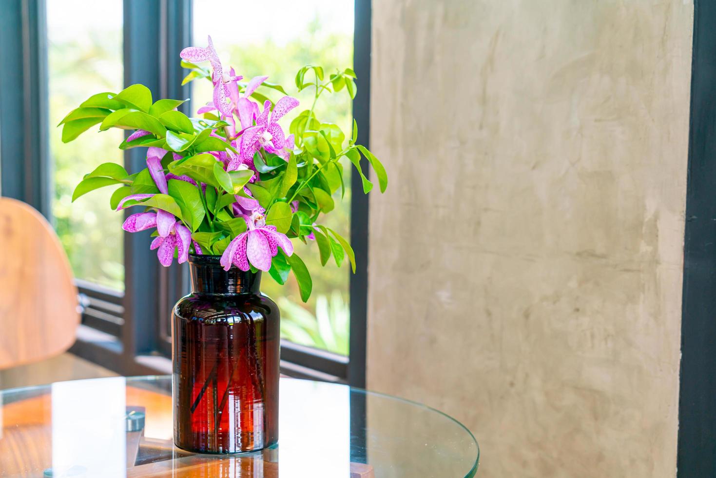 Orchid flowers in vase decoration on table in coffee shop cafe restaurant photo