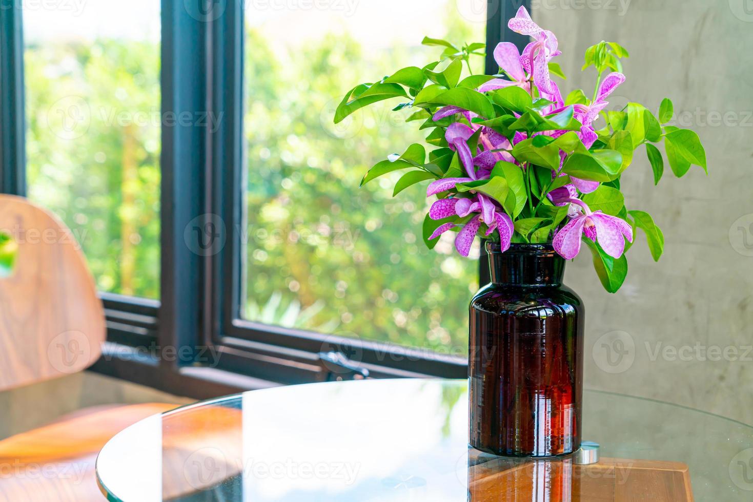 Orchid flowers in vase decoration on table in coffee shop cafe restaurant photo