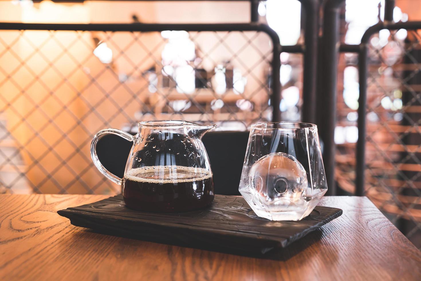 Tarro de café negro por goteo frío con vidrio y hielo en la cafetería, cafetería y restaurante foto