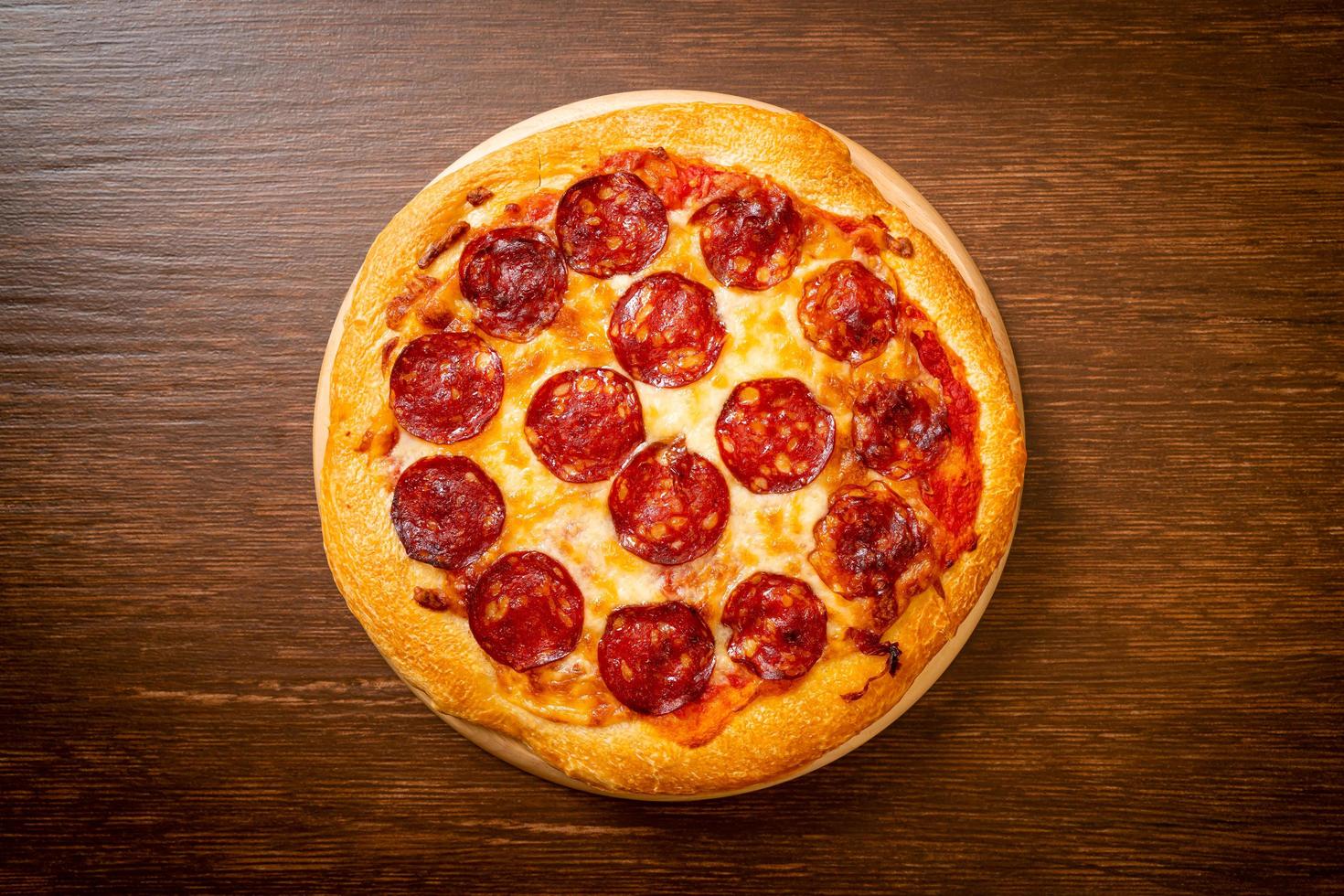 Pizza de pepperoni en bandeja de madera - estilo de comida italiana foto