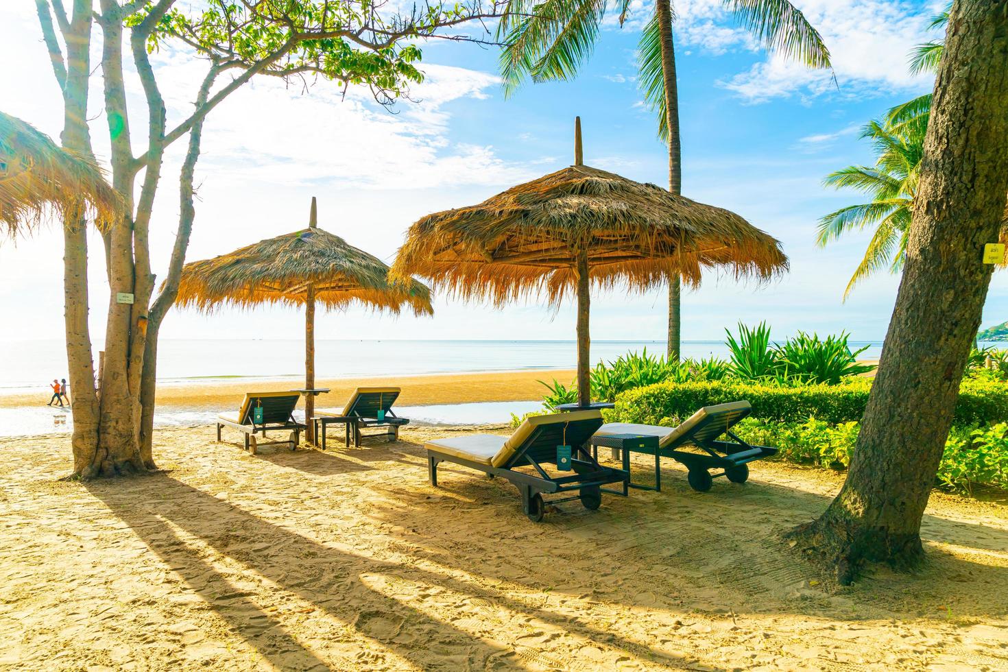 Sombrillas y sillas de playa con palmeras de coco y fondo de playa de mar y cielo azul - concepto de vacaciones y vacaciones foto