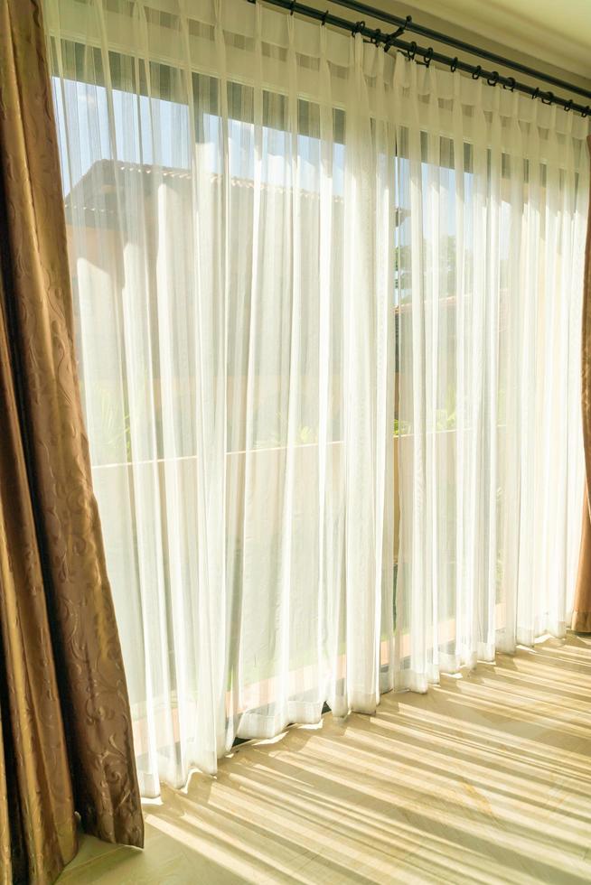 Hermosa cortina con luz solar desde la ventana de vidrio foto