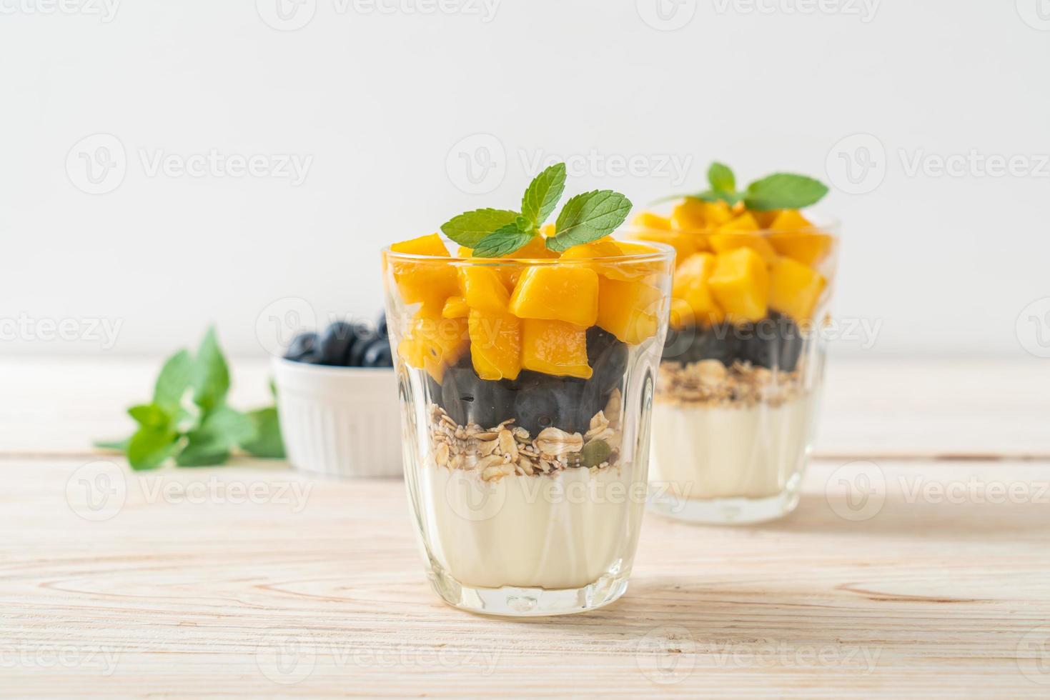 mango fresco casero y arándanos frescos con yogur y granola - estilo de comida saludable foto