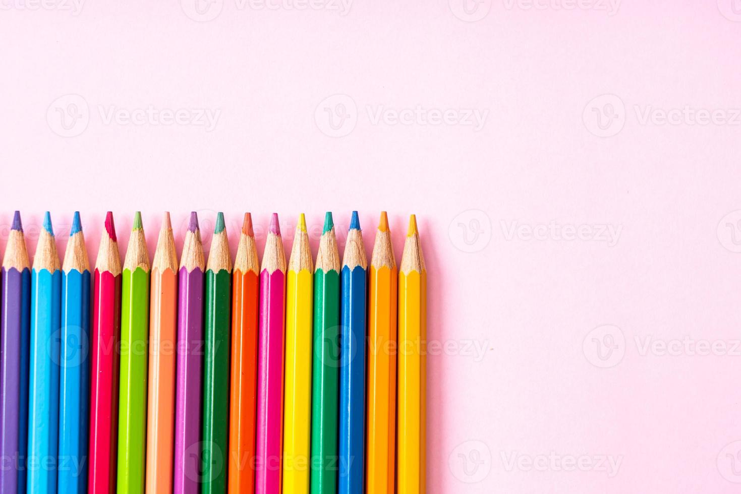 Colored pencils on pink background with copy space photo