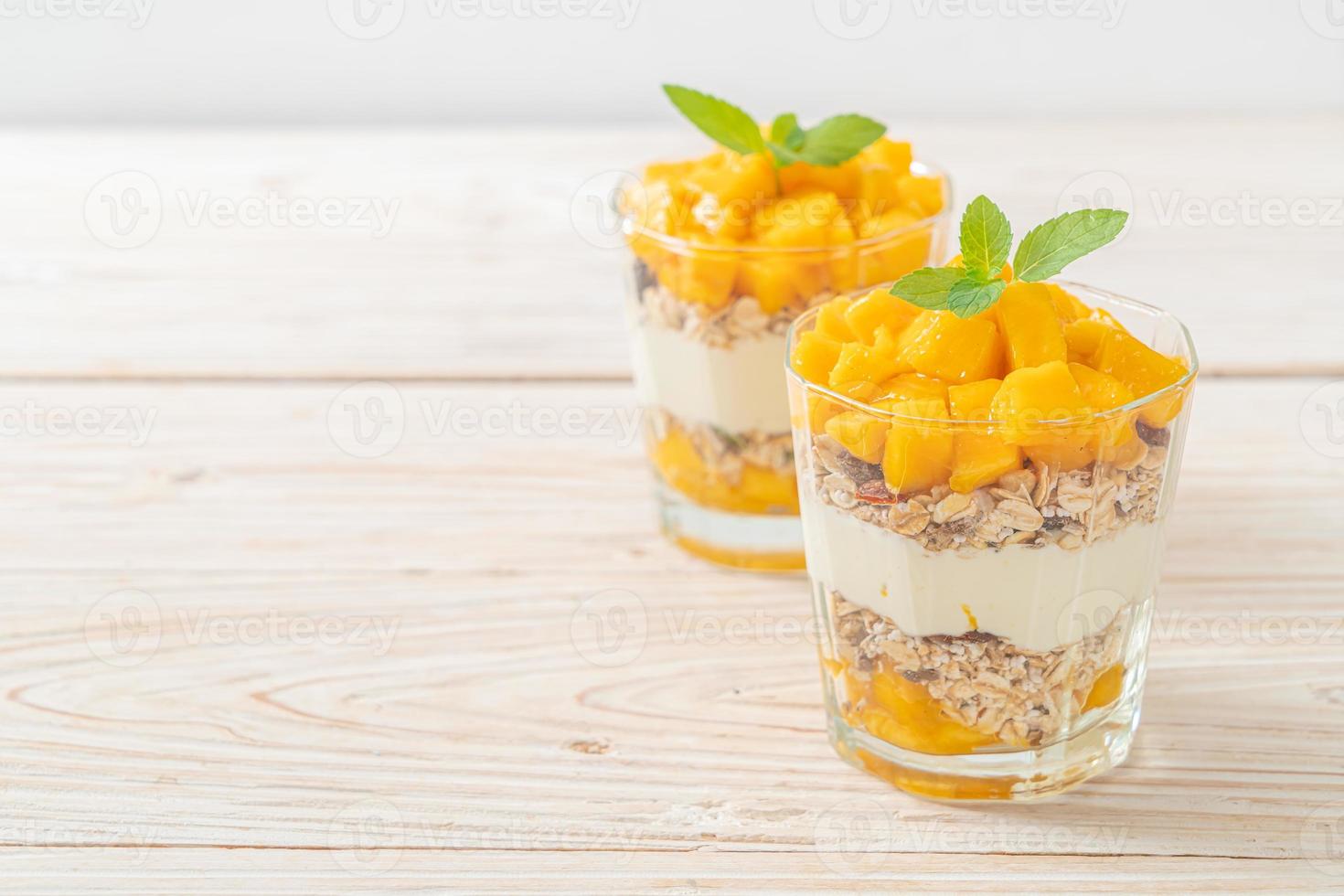 Yogur de mango fresco con granola en vidrio - estilo de comida saludable foto