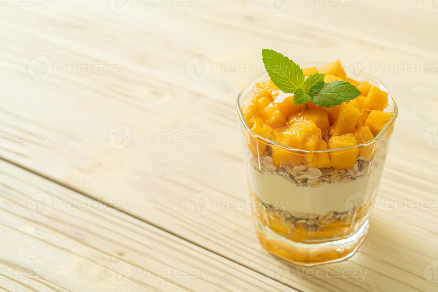 Yogur de mango fresco con granola en vidrio - estilo de comida saludable foto