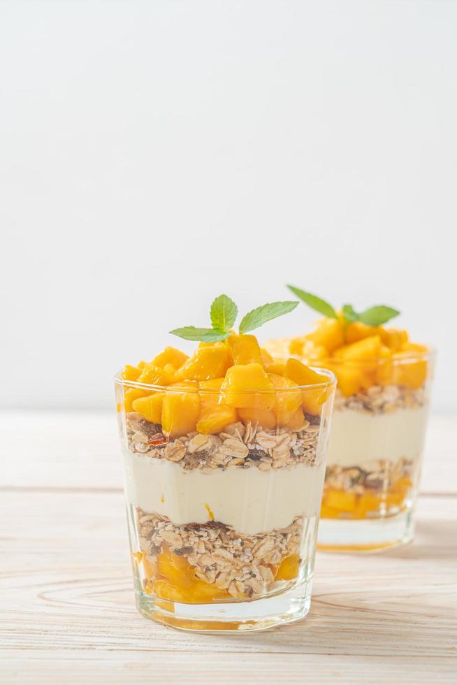 Yogur de mango fresco con granola en vidrio - estilo de comida saludable foto