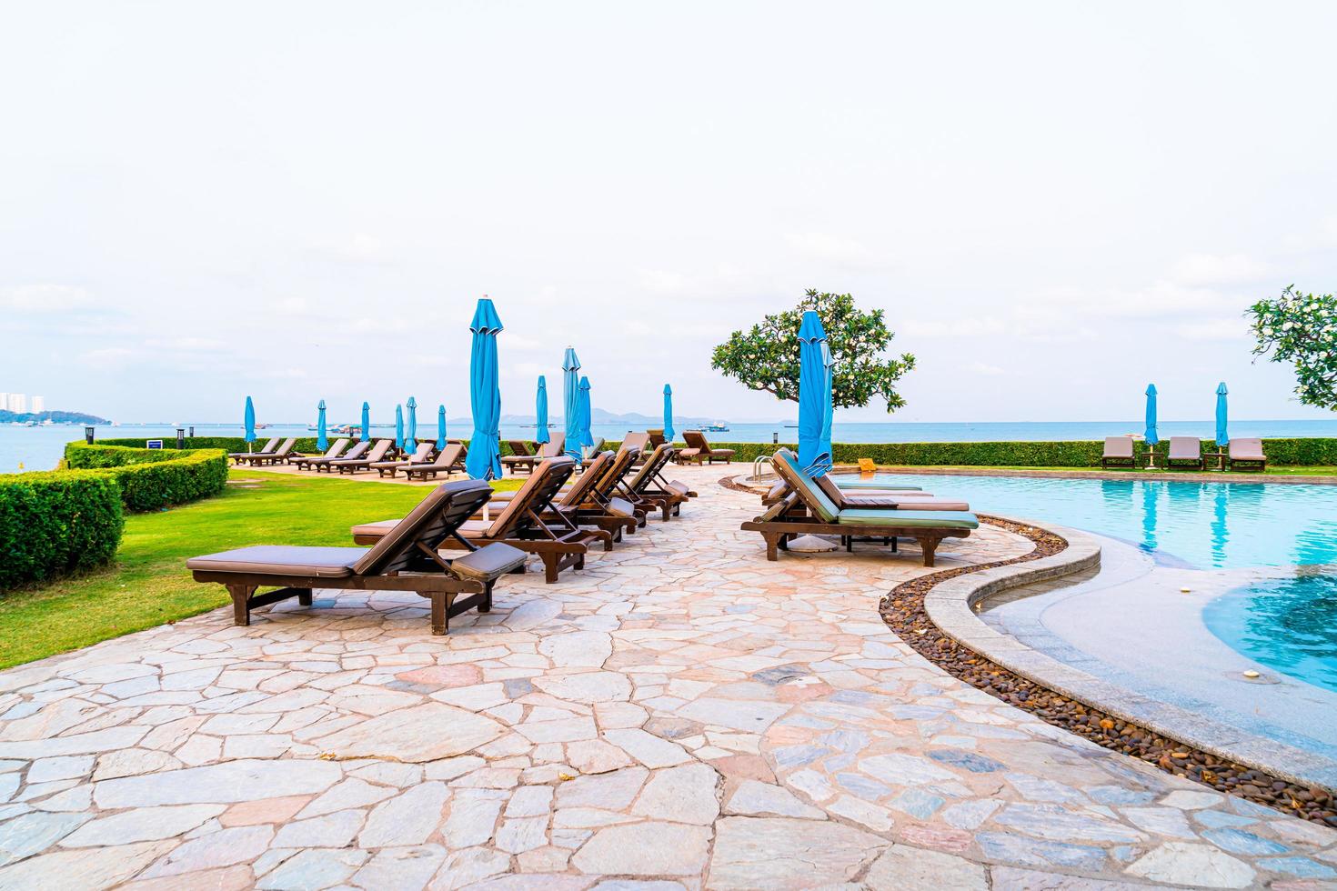 piscinas de sillas o piscinas de cama y sombrillas alrededor de la piscina con fondo de playa de mar foto