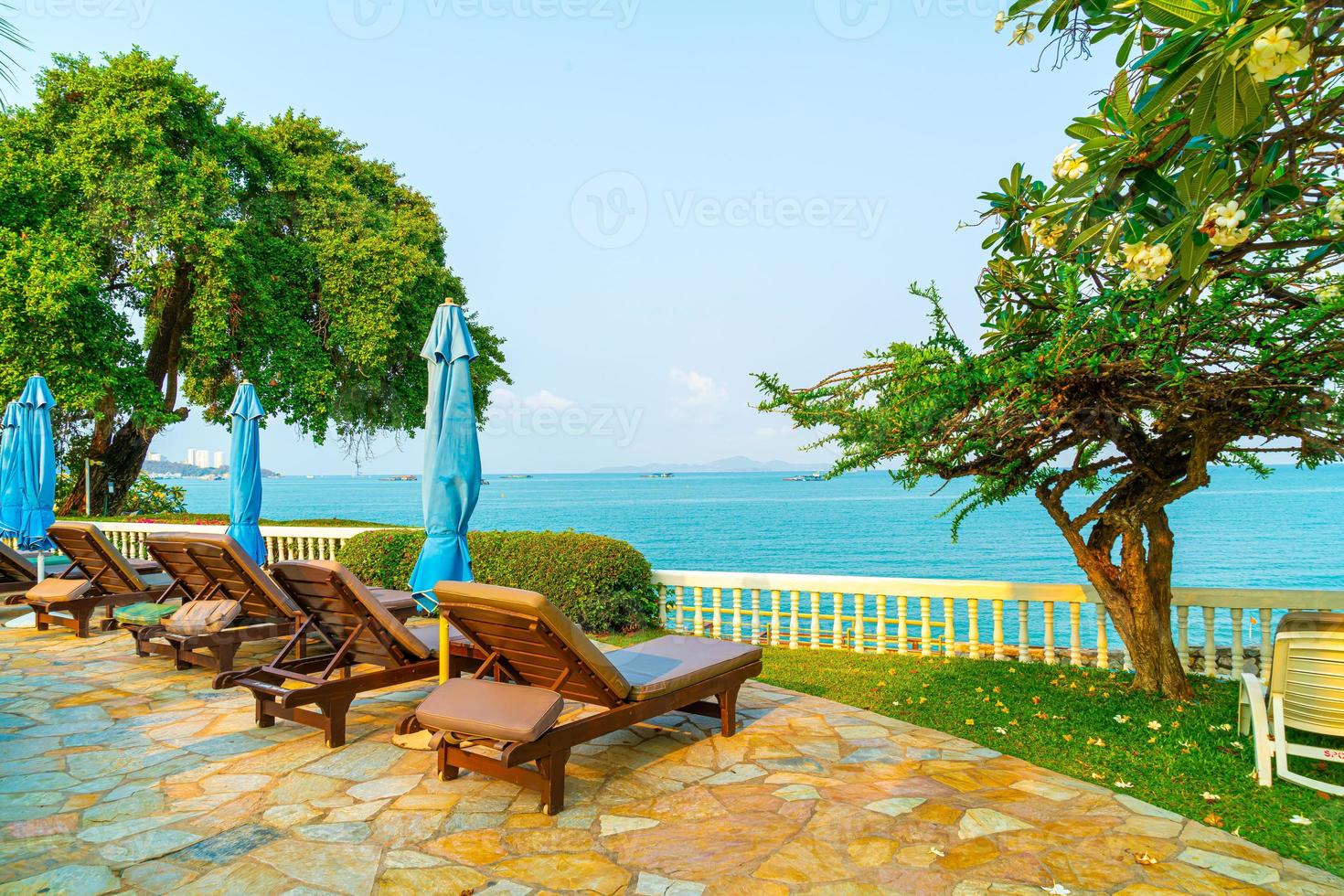 Chair pools and umbrellas around swimming pool with coconut palm trees - Holidays and vacation concept photo