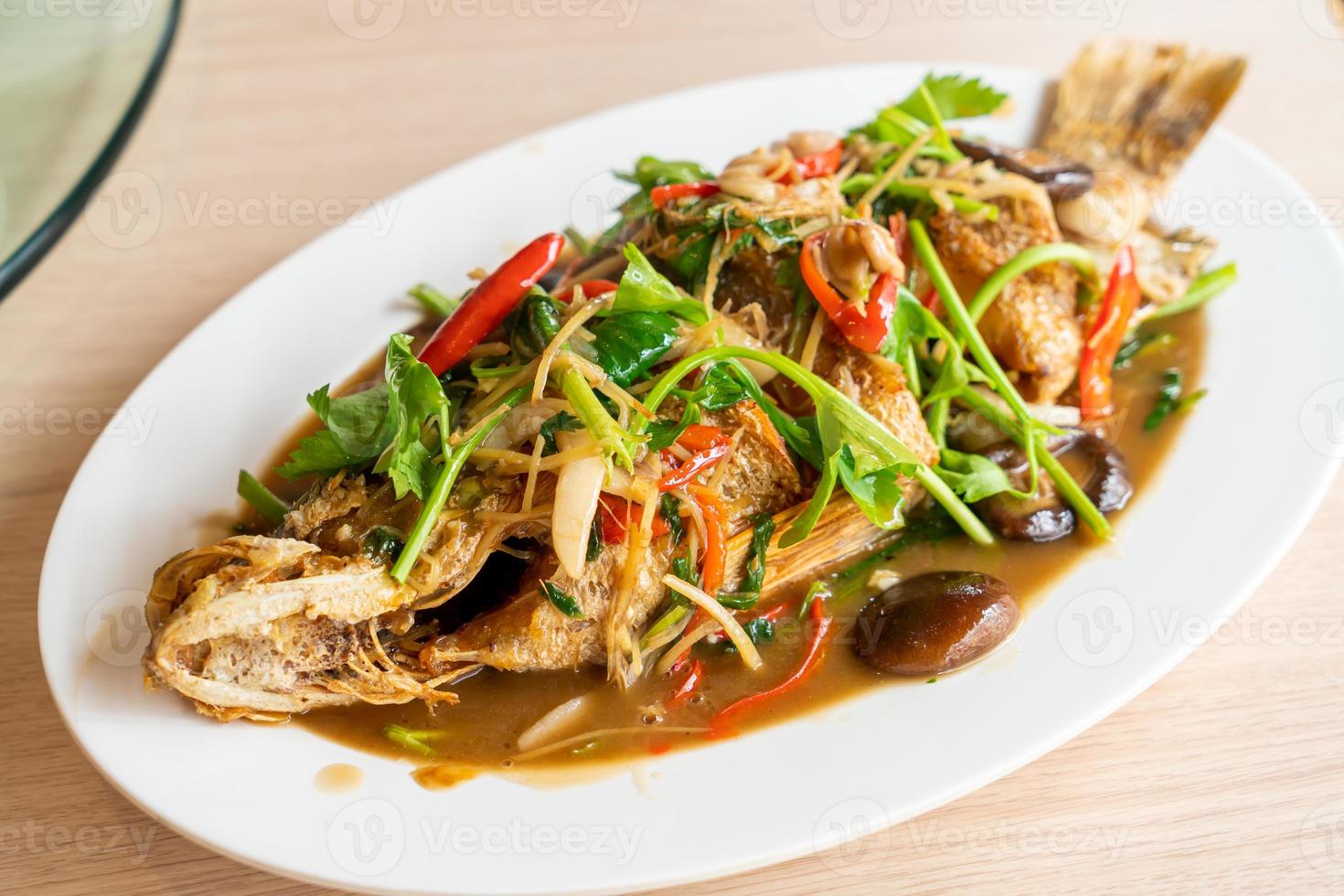 Deep-fried sea bass fish with sweet sauce and trimmings - Asian food style photo