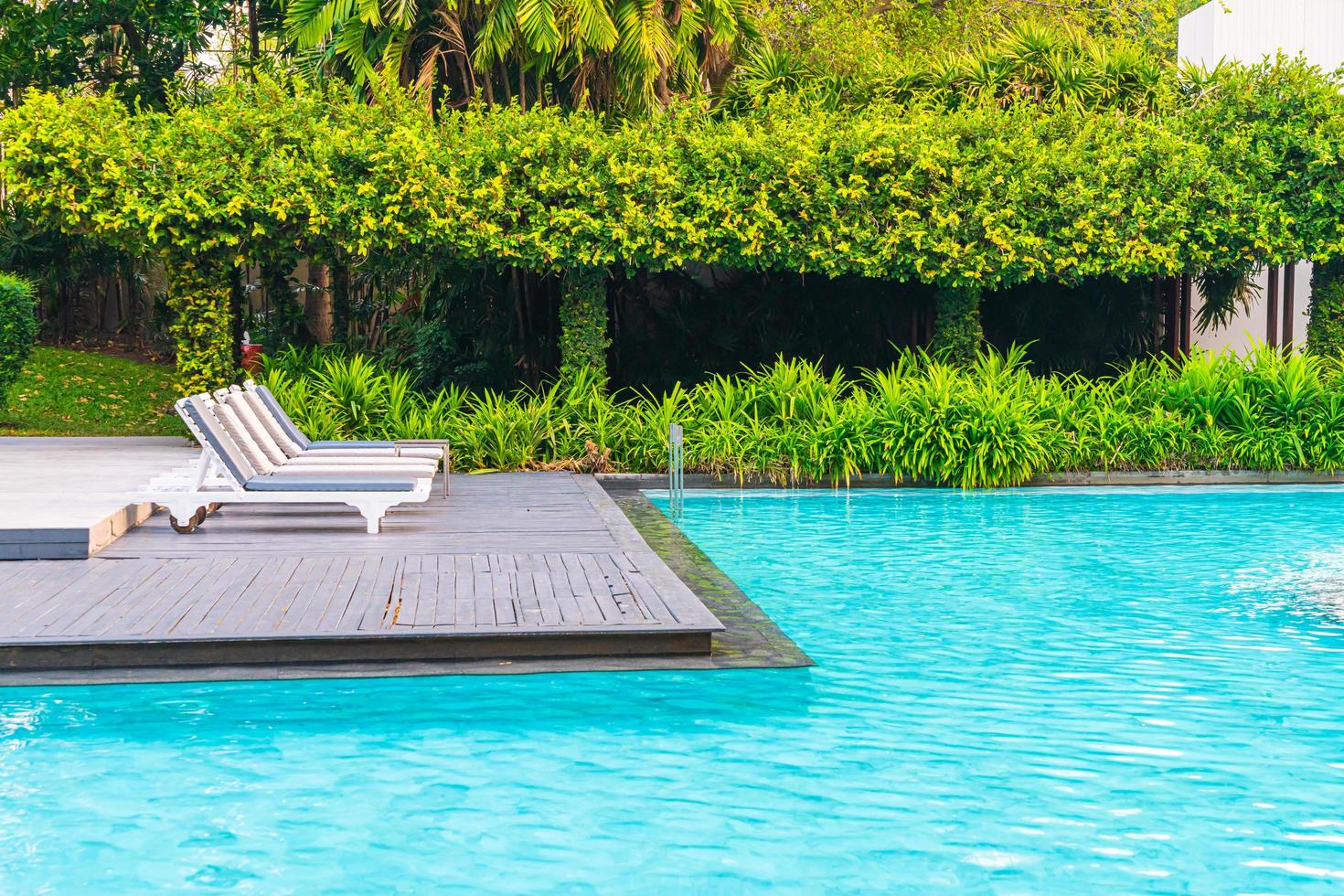 Piscina de sillas alrededor de piscinas en el hotel resort - vacaciones y concepto de vacaciones foto