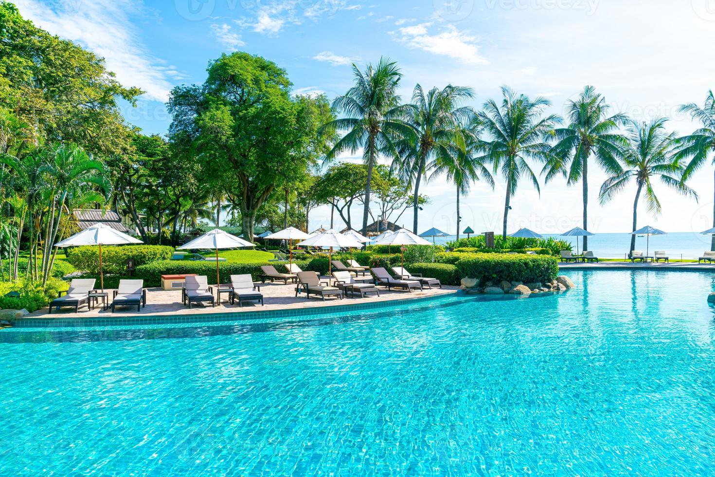 Beautiful umbrella and chair around swimming pool in hotel and resort photo